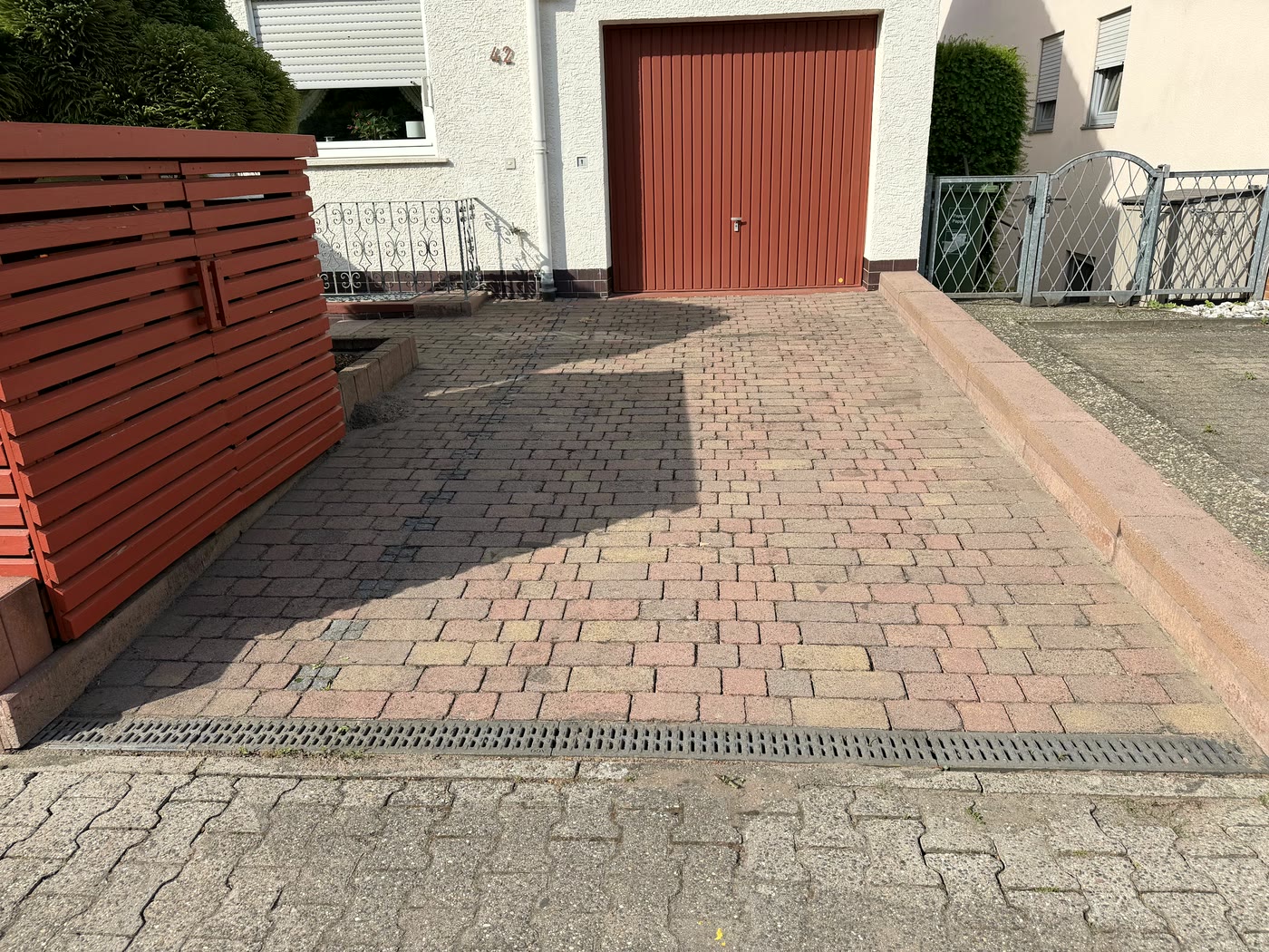 Frisch gereinigte, rötliche Pflastereinfahrt vor einem Garagentor