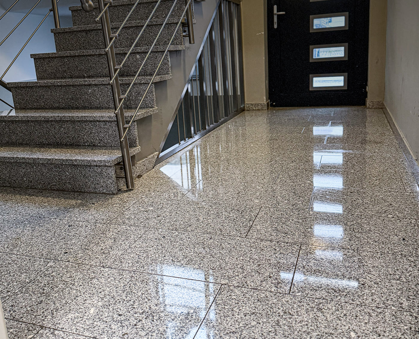 Glänzender Granitboden und Treppe mit Edelstahlgeländer in einem Mehrfamilienhaus